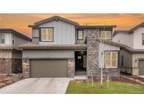 Two-story home boasts a stylish design with stone accents and a neutral color palette, set against a vibrant sunset sky at 533 Red Thistle Dr, Highlands Ranch, CO 80126