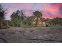 Charming brick home with a white picket fence and mature trees under a beautiful sky at 5475 W 1St Ave, Lakewood, CO 80226