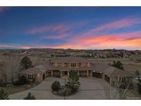 Stunning aerial view of a luxurious home with a circular driveway and manicured landscaping at dusk at 5625 Twilight Way, Parker, CO 80134