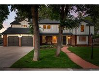 Charming two-story home features a brick and white facade, attached garage, and a beautiful green lawn at 2684 Taft Ct, Lakewood, CO 80215