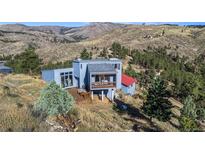 Stunning view of the exterior of a mountainside home with a wood deck and views of the mountains and surrounding trees at 319 Camino Bosque, Boulder, CO 80302