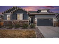 Charming home exterior featuring a stone facade, two-car garage, and manicured landscaping at 11346 Kittredge St, Commerce City, CO 80022