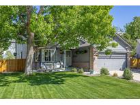 Charming gray home featuring a well-manicured lawn, inviting front porch, and mature shade tree at 11760 Eudora Ct, Thornton, CO 80233