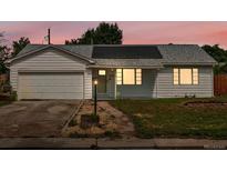 Charming ranch-style home featuring solar panels, attached garage, and well-lit entry, set against a beautiful sunset sky at 1670 Oakland St, Aurora, CO 80010