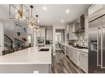 Modern kitchen boasts pendant lighting, stainless steel appliances, and a large island perfect for entertaining at 5964 E 141St Ave, Thornton, CO 80602