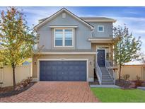 Charming two-story home with blue garage door, brick driveway and well-manicured landscaping at 17938 E 54Th Ave, Denver, CO 80249