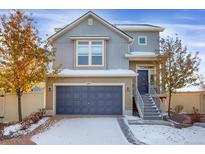 Charming two-story home featuring a blue garage door and matching front door with snowy landscaping at 17938 E 54Th Ave, Denver, CO 80249