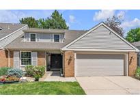 Charming home featuring a two-car garage, brick accents, lush greenery, and a well-manicured lawn, offering great curb appeal at 7183 S Poplar St, Centennial, CO 80112