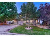 Charming stone-accented home with a well-maintained lawn and mature trees at 12350 Turquoise Terrace St, Castle Pines, CO 80108