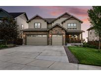Two-story home boasts a stone facade, attached three-car garage, and a covered porch at 7949 S Elk Way, Aurora, CO 80016