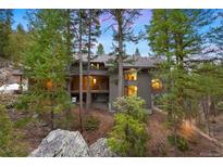 Stunning exterior view of a multi-level home nestled among tall trees and natural rock formations at 3816 Spring Valley Trl, Evergreen, CO 80439