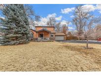 Charming two-story home with covered porch, lush lawn, and attached garage at 2202 Dover St, Lakewood, CO 80215