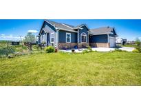 Charming blue two-story home with a well-maintained lawn and brick accents on a sunny day at 59466 E Commanche Way, Strasburg, CO 80136