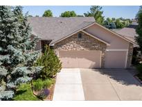 Lovely home featuring a stone facade and a three-car garage with mature trees at 1376 Banner Cir, Erie, CO 80516