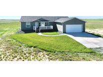 Charming single-story home featuring a lush green lawn, inviting front porch, and attached two-car garage at 9 Timberlake Ct, Byers, CO 80103