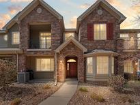 Charming stone townhome with a well-maintained front yard, covered balcony, and inviting front entrance at 15496 W 66Th Dr # B, Arvada, CO 80007
