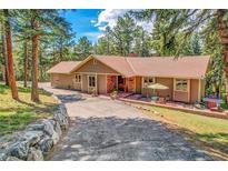 Charming single-story home with a brick-accented facade, inviting patio, and lush green landscaping at 7753 Red Fox Dr, Evergreen, CO 80439