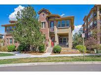Charming townhome with a red door, covered porch, and landscaped front yard on a sunny day at 7814 Inverness Blvd, Englewood, CO 80112
