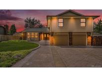 Inviting two-story home featuring a manicured lawn, two-car garage, and beautiful brick and siding accents at 7285 S Yukon Ct, Littleton, CO 80128