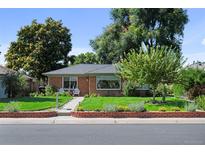 Charming brick home featuring a well-maintained lawn and cozy front porch seating area at 2649 N Cook St, Denver, CO 80205