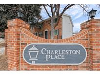 Charming brick townhome in Charleston Place featuring a classic sign and well-maintained landscaping at 13993 E Jewell Ave, Aurora, CO 80012