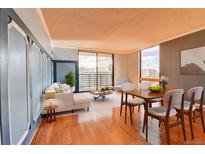 Bright living room featuring wood floors, a modern sofa, and a dining area with city views at 1301 Speer Blvd # 1008, Denver, CO 80204