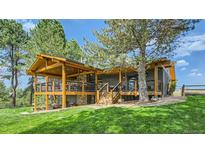A back view of the house with a wooden deck featuring cable railing and a stone accent wall underneath at 2231 Meadow Green Cir, Franktown, CO 80116