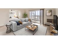 Bright living room with balcony, light gray sofa, and stylish decor that seamlessly connects to the bedroom at 9335 E Center Ave # 4B, Denver, CO 80247