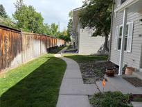 Home's front yard with sidewalk, wooden fence, green grass, and welcoming front porch at 1967 S Oakland Way, Aurora, CO 80014