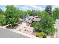 Charming two-story home with lush landscaping, a brick facade, and an attached two-car garage at 1590 S Macon St, Aurora, CO 80012
