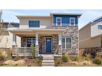 Two-story home featuring a stone facade, inviting front porch, and attractive blue door at 868 N Quatar St, Aurora, CO 80018