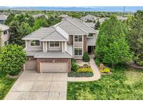 Charming two-story home with manicured lawn, mature trees, and a brick-accented, two-car garage at 10529 Dacre Pl, Lone Tree, CO 80124