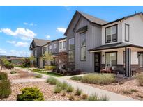 Charming townhomes with modern gray and white exteriors, neat landscaping, and inviting sidewalks under a bright blue sky at 19593 W 93Rd Ln # E, Arvada, CO 80007