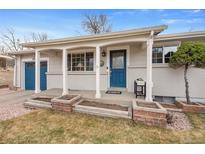 Charming single-story home with a beautiful blue front door, brick planters, and well-maintained landscaping at 1359 Chambers Rd, Aurora, CO 80011