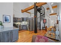 Open kitchen with stainless steel appliances and a unique spiral staircase, blending modern convenience with architectural flair at 1555 California St # 414, Denver, CO 80202