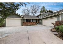 Charming exterior showcasing a well-maintained lawn and a two-car garage with stone detailing along the facade at 7676 S Olive Cir, Centennial, CO 80112
