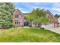 Charming two-story brick home with a well-manicured lawn, mature trees, and an attached two-car garage at 51 Falcon Hills Dr, Highlands Ranch, CO 80126