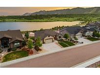 Beautiful stucco home with an attached two-car garage, manicured lawn and lake views at sunset at 2891 Waterfront Dr, Monument, CO 80132