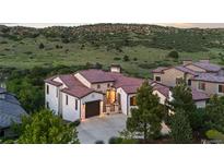 Stunning home exterior with tile roof, stone accents, three-car garage, and landscaped yard at 8278 Raphael Ln, Littleton, CO 80125