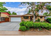 Charming brick home with a well-maintained front yard, mature tree, and a large driveway at 1285 Elder St, Denver, CO 80221