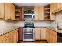 Bright kitchen features wood cabinets, granite countertops, stainless steel appliances, and stylish subway tile backsplash at 655 S Alton Way # 6A, Denver, CO 80247