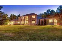 Expansive two-story home with brick facade, mature trees, and lush green lawn at 11345 W 38Th Ave, Wheat Ridge, CO 80033