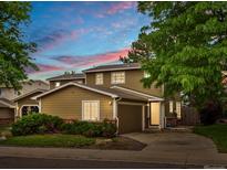 Charming two-story home featuring an attached garage, mature trees, and colorful bushes, captured during a vibrant sunset at 12599 Elm St, Thornton, CO 80241