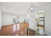 Bright and airy living room with hardwood floors and a view of the kitchen and walk-out balcony at 1250 S Monaco Pkwy # 44, Denver, CO 80224