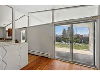 Open living room featuring large windows and hardwood floors with access to the backyard at 1573 S Dexter Way, Denver, CO 80222