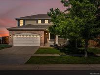 Charming two-story home featuring a brick facade and well-manicured lawn at dusk at 4816 S Elk Way, Aurora, CO 80016