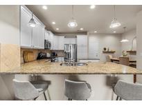 Bright kitchen features granite countertops, stainless steel appliances and a breakfast bar at 9071 E Phillips Dr, Centennial, CO 80112