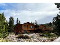 Stunning two-story home with a wooden exterior, charming deck, and lush, mature trees at 29825 Kennedy Gulch Rd, Conifer, CO 80433