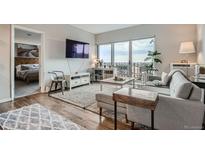 Bright living room with modern furniture, hardwood floors, and access to a balcony with great city views at 1150 Vine St # 1006, Denver, CO 80206