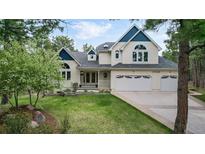 Charming two-story home with blue and white accents, lush green lawn, and well-manicured landscaping at 17420 Caribou Dr, Monument, CO 80132